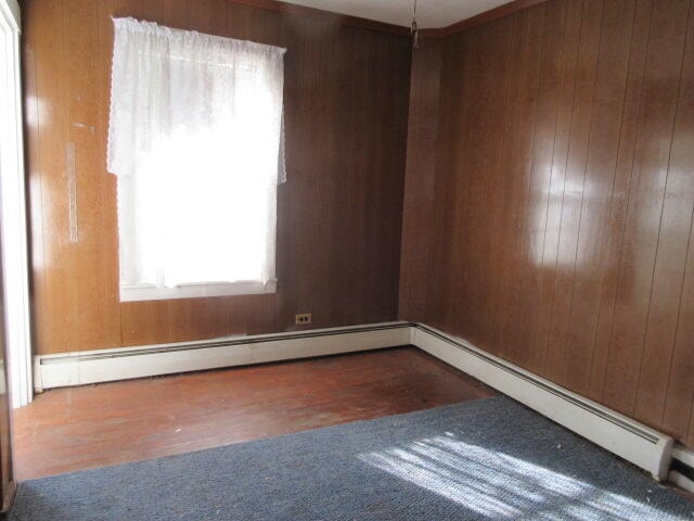 spare room featuring baseboard heating and wood walls