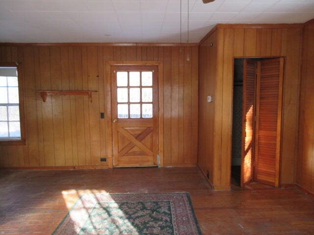 doorway featuring wooden walls and wood-type flooring