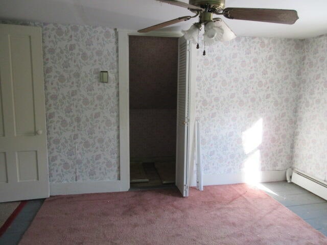 carpeted spare room featuring ceiling fan and baseboard heating