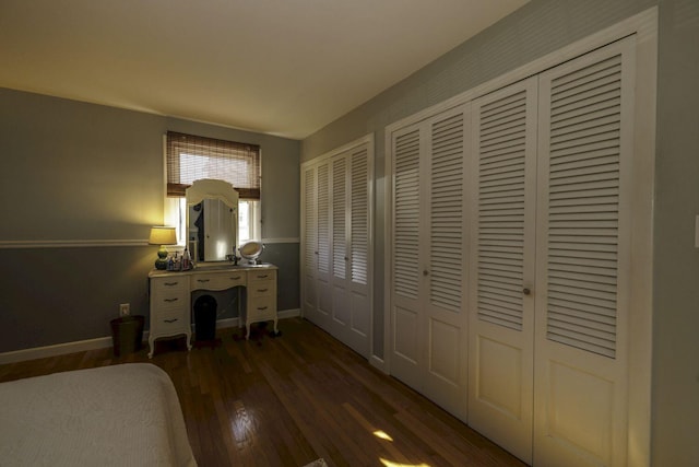 bedroom featuring dark hardwood / wood-style flooring and multiple closets