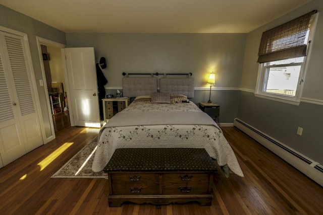 bedroom with a closet, dark hardwood / wood-style floors, and a baseboard heating unit