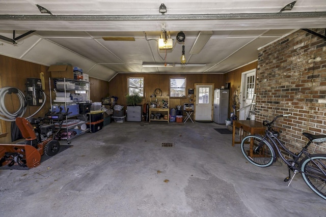 garage with white refrigerator, a garage door opener, and wood walls