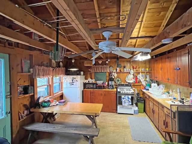 kitchen with lofted ceiling, ceiling fan, white appliances, and wooden walls