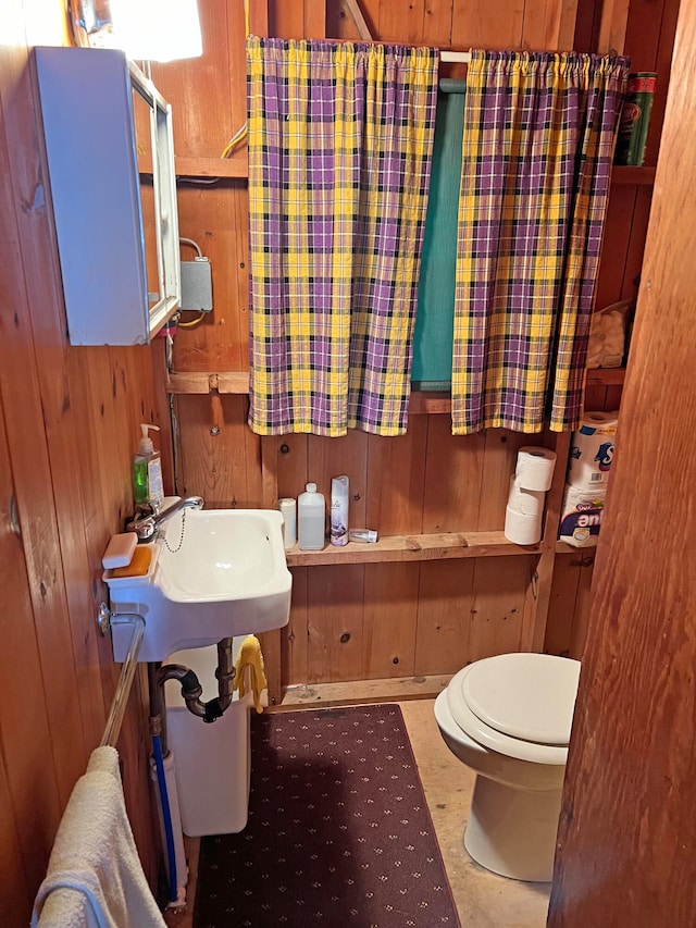 bathroom featuring wood walls, sink, and toilet