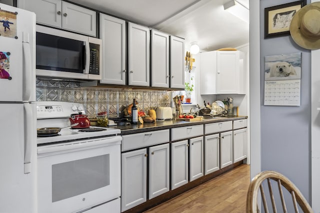 kitchen featuring decorative backsplash, light wood-type flooring, white appliances, and white cabinets