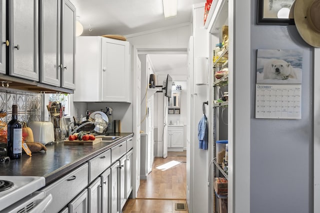 kitchen featuring light hardwood / wood-style floors, sink, and vaulted ceiling