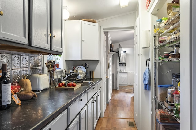 kitchen featuring gray cabinets, sink, vaulted ceiling, and hardwood / wood-style flooring