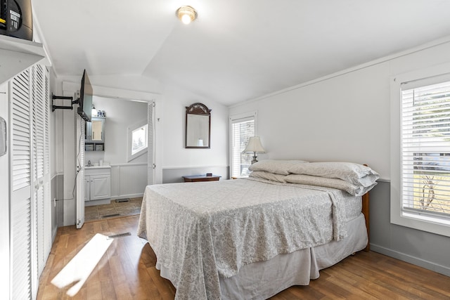 bedroom featuring hardwood / wood-style flooring, vaulted ceiling, and multiple windows