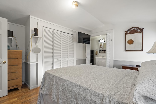 bedroom featuring hardwood / wood-style floors, lofted ceiling, connected bathroom, and a closet