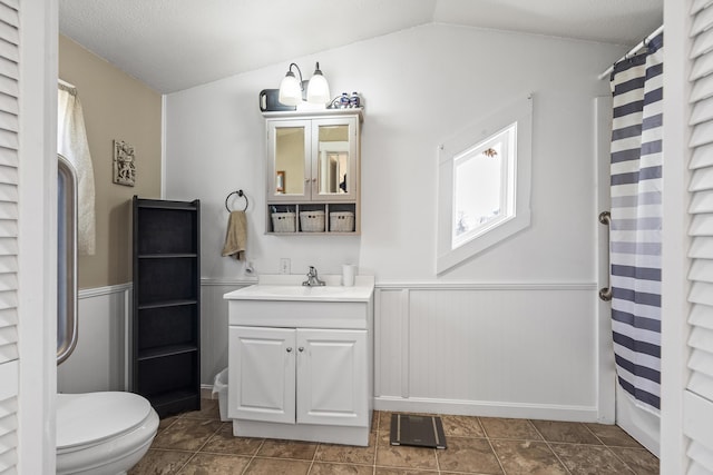 bathroom featuring tile patterned flooring, vanity, toilet, and lofted ceiling