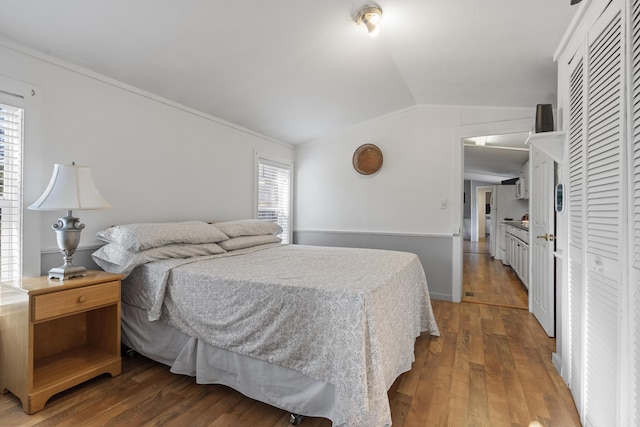 bedroom with hardwood / wood-style flooring, vaulted ceiling, and multiple windows