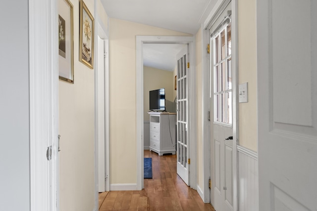 corridor featuring hardwood / wood-style floors and vaulted ceiling