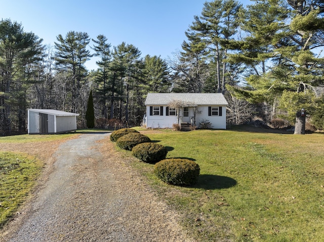 single story home featuring an outbuilding and a front lawn