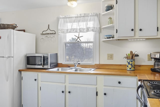 kitchen featuring wood counters, sink, electric range, white fridge, and white cabinetry