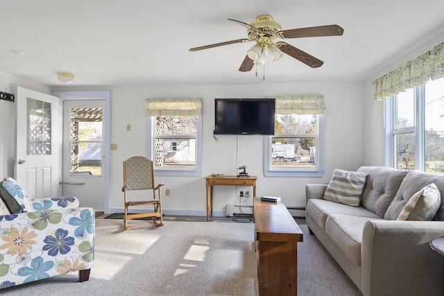 carpeted living room with ceiling fan, baseboard heating, and a wealth of natural light