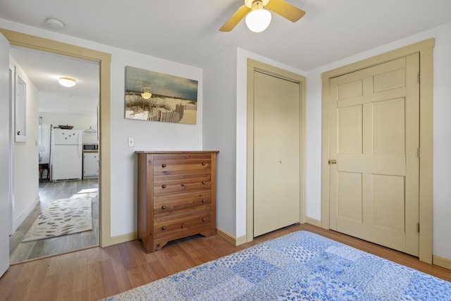 bedroom featuring a closet, light wood-type flooring, white fridge, and ceiling fan