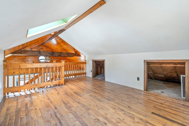 additional living space featuring hardwood / wood-style flooring, ceiling fan, and vaulted ceiling with skylight