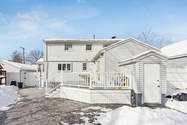 snow covered back of property with a storage unit