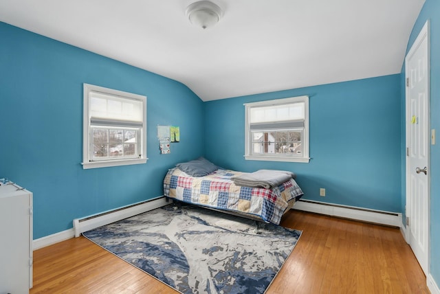 bedroom featuring a baseboard heating unit, lofted ceiling, and light hardwood / wood-style flooring