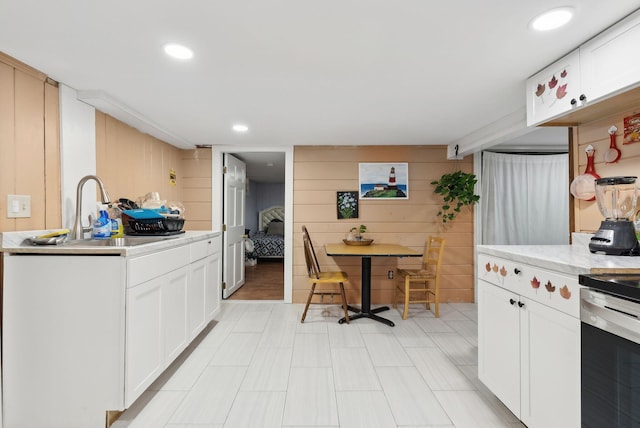 kitchen featuring white cabinets, sink, and wood walls