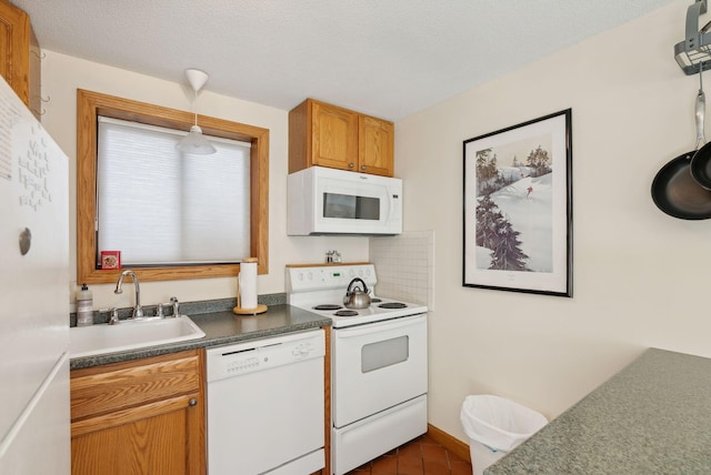 kitchen featuring sink, hanging light fixtures, dark tile patterned floors, a textured ceiling, and white appliances