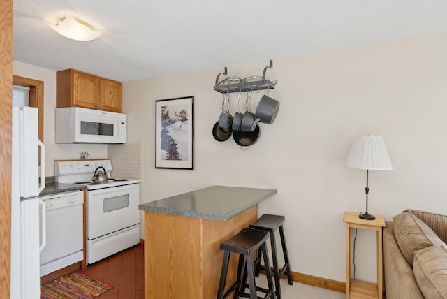 kitchen featuring a breakfast bar area, kitchen peninsula, and white appliances