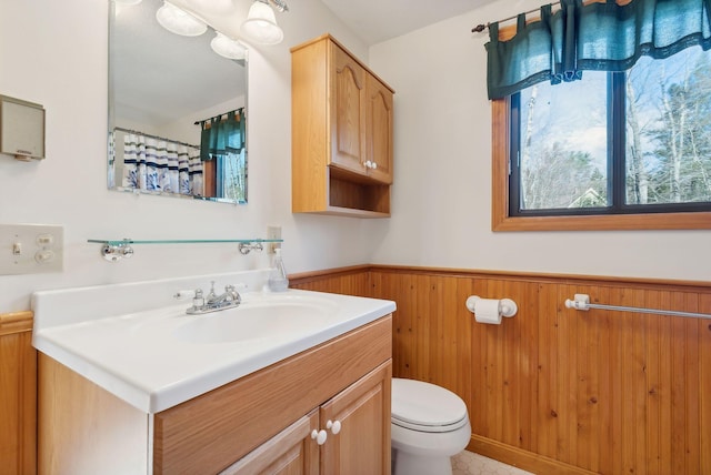 bathroom featuring vanity, toilet, and wooden walls