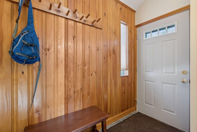 mudroom with wooden walls, lofted ceiling, and dark colored carpet