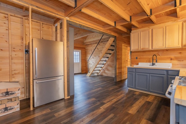 kitchen with wood walls, sink, and stainless steel refrigerator