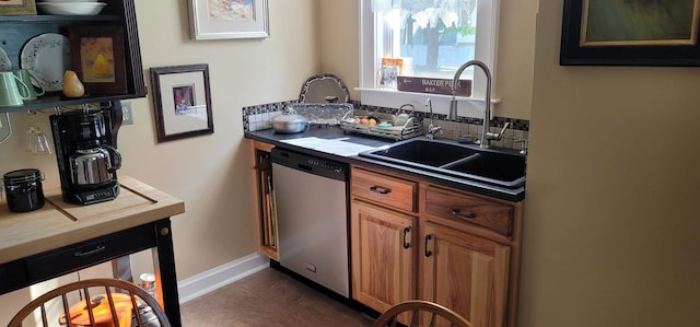 kitchen featuring stainless steel dishwasher, sink, and dark tile patterned flooring