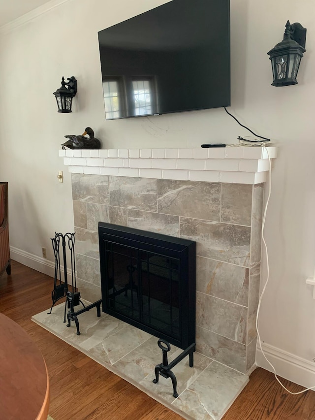 room details with hardwood / wood-style floors, ornamental molding, and a tiled fireplace