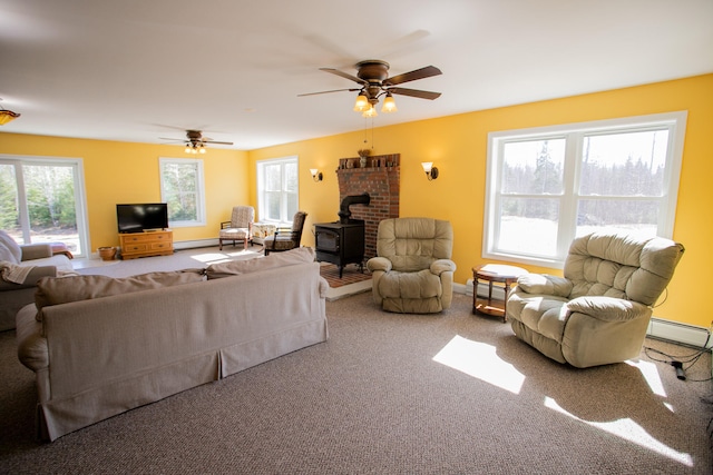 carpeted living room featuring ceiling fan, a wood stove, and baseboard heating