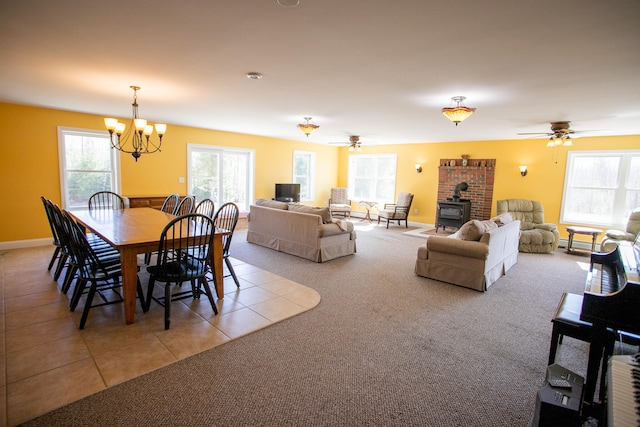 tiled dining area with ceiling fan with notable chandelier and a wood stove