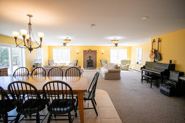 carpeted dining room featuring a wood stove, plenty of natural light, and ceiling fan with notable chandelier