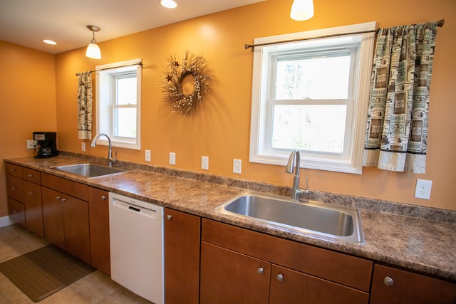 kitchen with white dishwasher, decorative light fixtures, light tile patterned floors, and sink