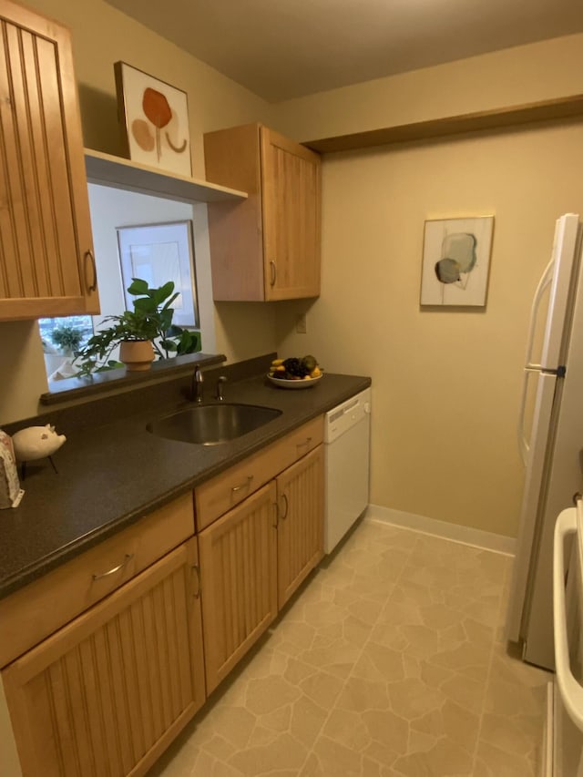 kitchen with white appliances, sink, and light brown cabinets