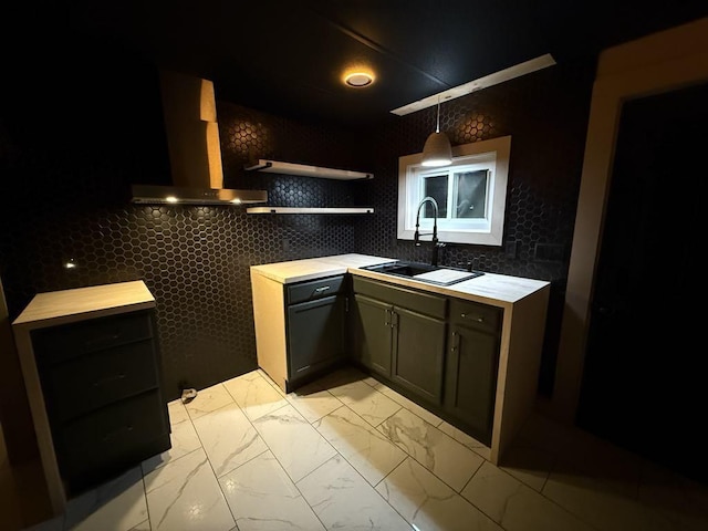 kitchen featuring backsplash, sink, wall chimney exhaust hood, and pendant lighting