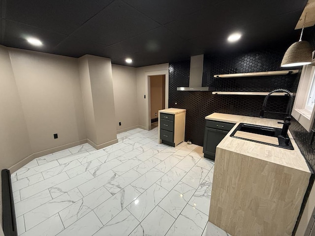 kitchen with sink, decorative light fixtures, wall chimney range hood, and wood counters