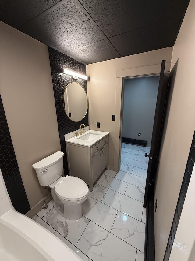 bathroom featuring a drop ceiling, vanity, and toilet