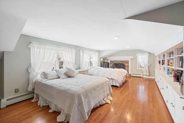 bedroom featuring vaulted ceiling, multiple windows, and a baseboard heating unit