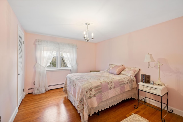 bedroom featuring baseboard heating, a closet, light hardwood / wood-style flooring, and an inviting chandelier