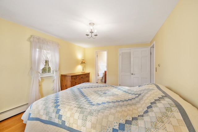 bedroom with ensuite bathroom, a closet, a baseboard radiator, and wood-type flooring