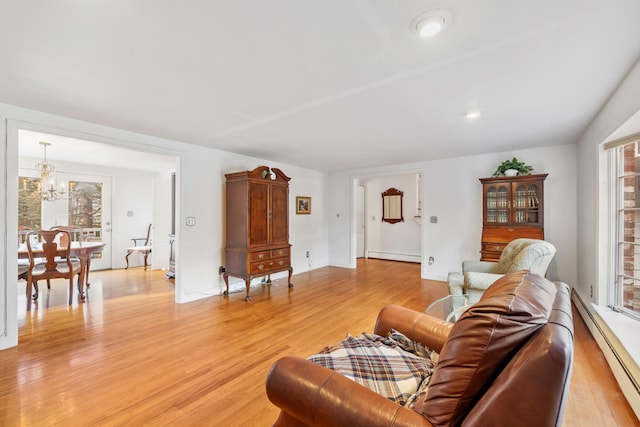 living room featuring a chandelier, light wood-type flooring, and a baseboard heating unit