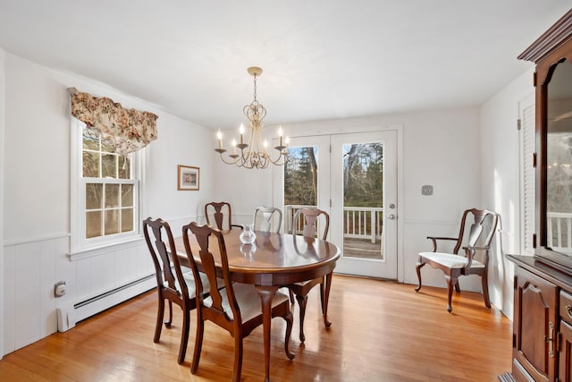 dining room featuring a notable chandelier, a baseboard heating unit, and light wood-type flooring