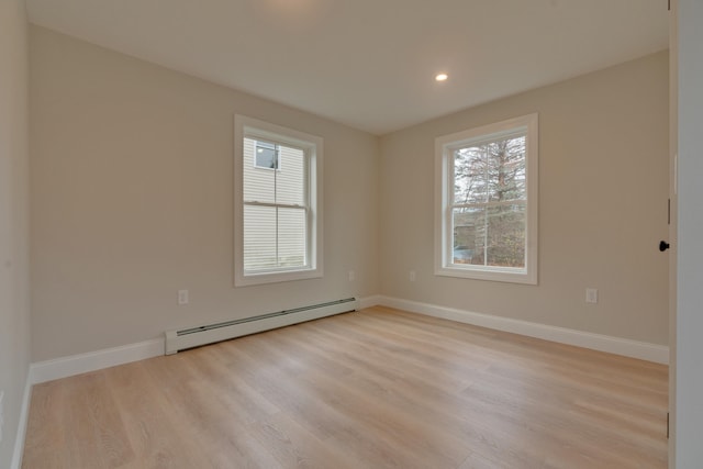 empty room featuring light wood-type flooring and a baseboard radiator