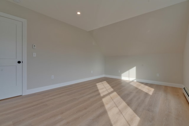 unfurnished room with light hardwood / wood-style floors, lofted ceiling, and a baseboard heating unit