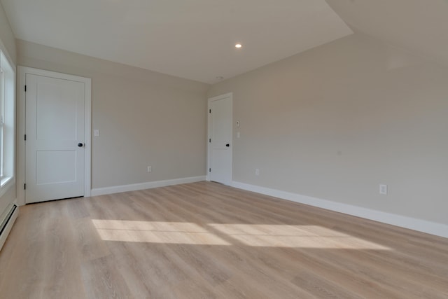 spare room with light wood-type flooring and vaulted ceiling