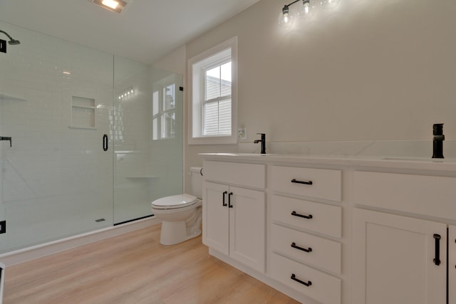 bathroom with vanity, toilet, wood-type flooring, and a shower with door