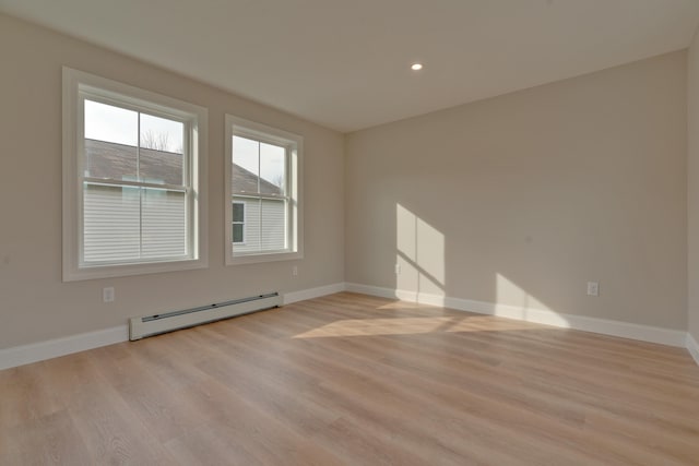 unfurnished room featuring a baseboard radiator and light hardwood / wood-style flooring