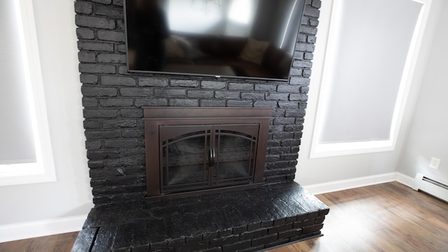 interior details featuring hardwood / wood-style flooring, a baseboard radiator, and a brick fireplace